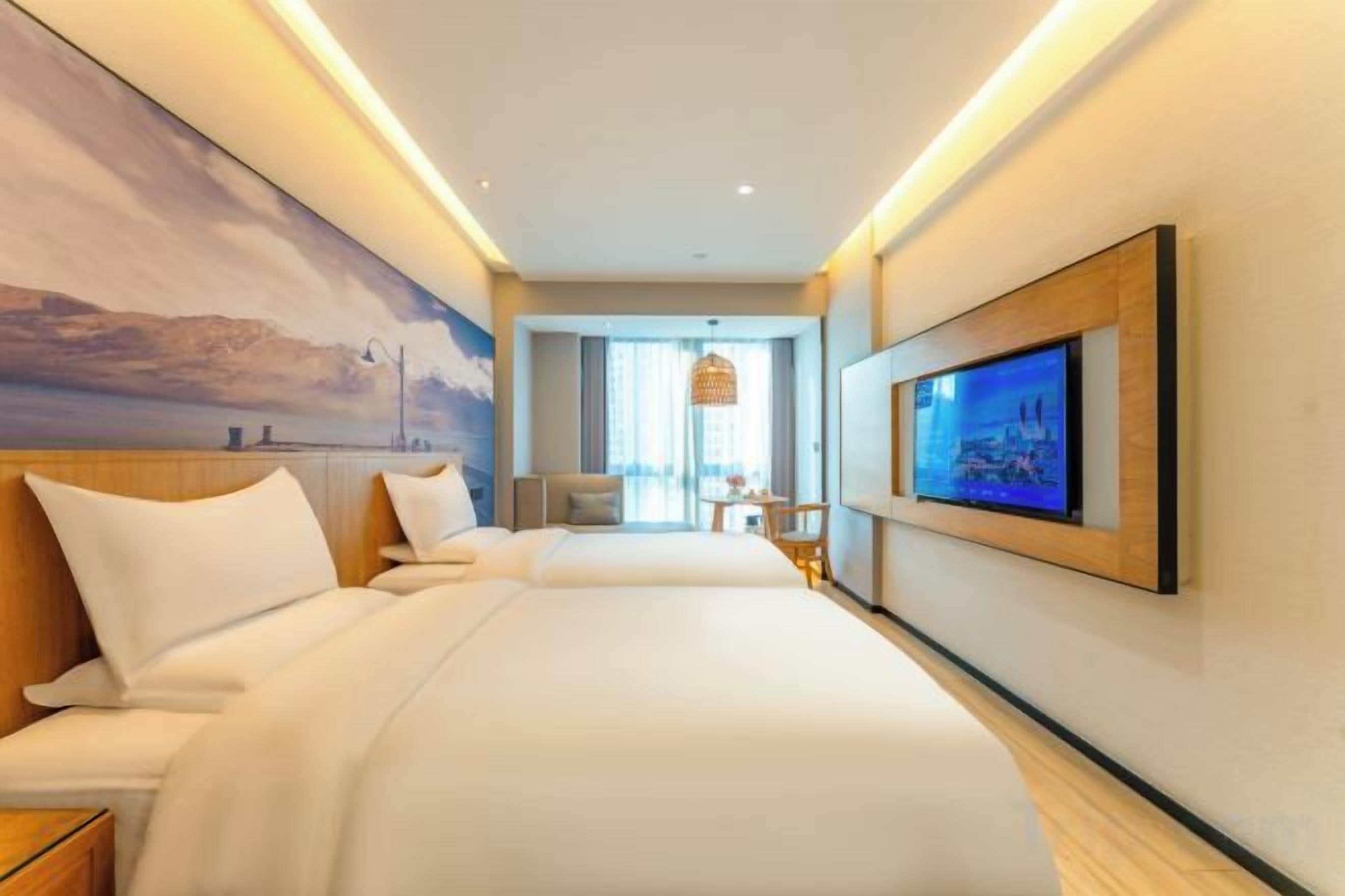Una habitación de hotel con una cama grande, televisión y un cuadro en la pared.