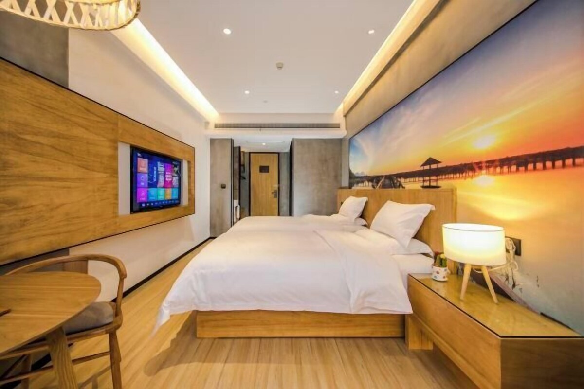 A modern hotel room with a large bed, a desk, and a TV on the wall.