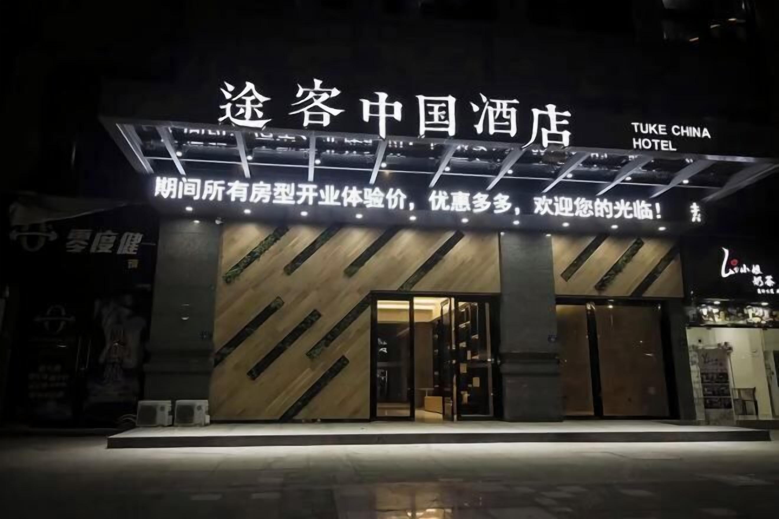A hotel entrance with a modern design, featuring a prominent sign with Chinese characters and English text.