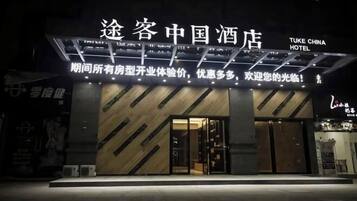 A hotel entrance with a modern design, featuring a prominent sign with Chinese characters and English text.