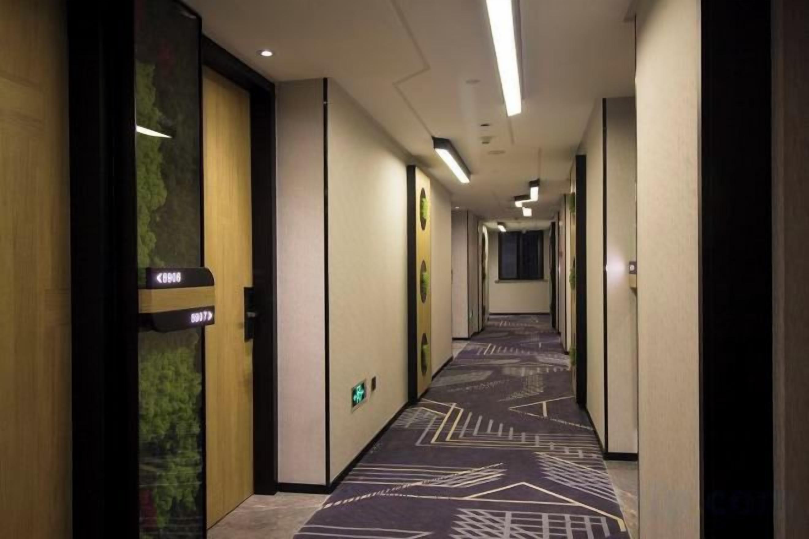 Passadís d'hotel amb sòls amb moqueta, portes a l'esquerra i un senyal que indica el número de habitació 8079.