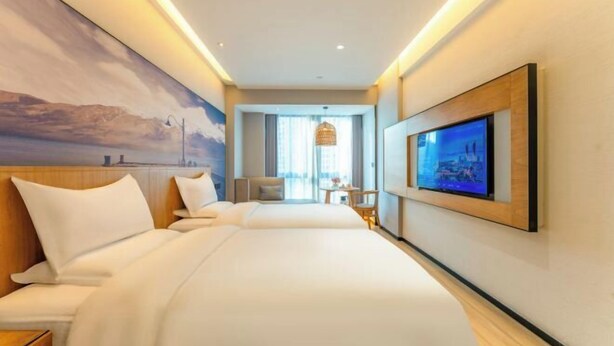 Habitación de hotel con una cama grande, un televisor montado en la pared y un cuadro.