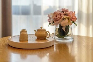 A table with a teapot and a tray, and a vase with flowers.