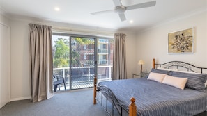 Relax in this serene bedroom with a large bed, ceiling fan, and sliding glass door leading to a balcony with a view.
