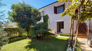 A well-maintained garden with a variety of plants and a paved pathway leading to a building with a wooden staircase. - 2 bedroom apartment in village Valbandon, 1 km distance from the beach (Fažana)
