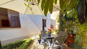A patio area with a table and chairs, surrounded by potted plants and a small garden. - 2 bedroom apartment in village Valbandon, 1 km distance from the beach (Fažana)