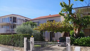 A residential building with a gated entrance, a parked car, and a tree in the foreground. - 2 bedroom apartment in village Valbandon, 1 km distance from the beach (Fažana)
