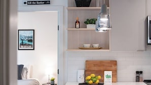 Una cocina moderna con encimera blanca, tabla de cortar de madera, cafetera y cesta de limones.