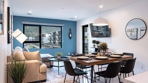 Un comedor moderno con una mesa de madera preparada para cuatro personas, rodeada de sillas negras.