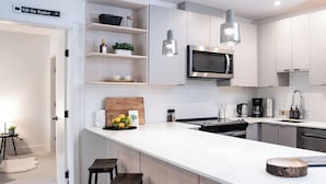 Una cocina moderna con armarios blancos, una isla central con taburetes, un microondas y una cafetera.