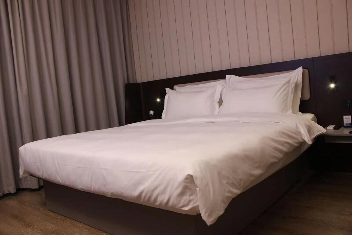 A neatly made bed with white linens in a hotel room.