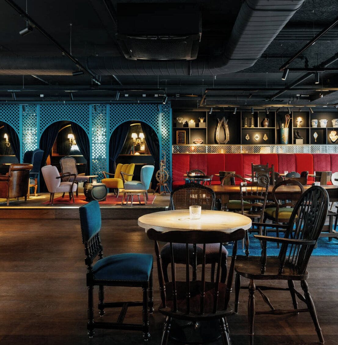 A restaurant interior with round tables, chairs, and a bar area.