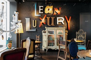A boutique hotel interior with a brick wall, a large 'LEON LUXURY' sign, antique furniture, and a vintage cabinet with glass doors. - Ruby Rosi Hotel Munich by IHG (Munich)
