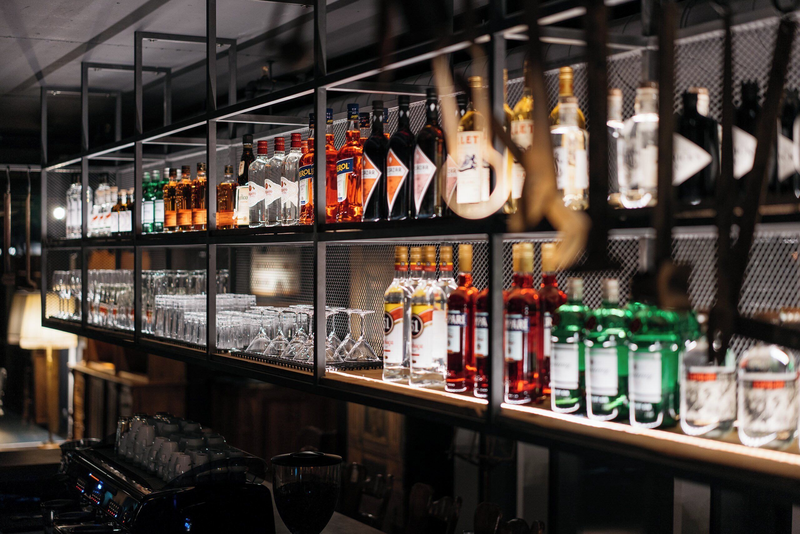 A bar area with shelves stocked with various liquor bottles and glasses.
