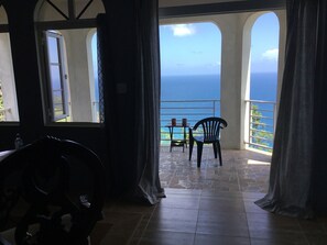 Ein Zimmer mit Meerblick, einem Tisch mit Stühlen und einer Bank.