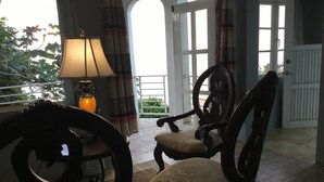 A room with a large window, a table with a lamp, and a chair.