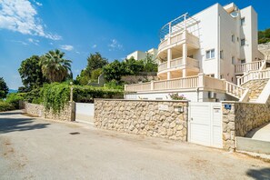 A multi-story building with balconies, a stone wall, and a clear sky. - Villa Borna Apartments - Deluxe Studio Apartment - br. 1 (Dubrovnik)