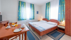 Ein Hotelzimmer mit Bett, Nachttischen, einem Schreibtisch mit Stuhl und einem Frühstückstisch.