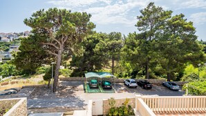 A parking area with covered carports and a view of a residential area with trees and houses.