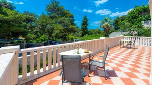 An outdoor patio with a checkered floor, a table with chairs, and a railing.