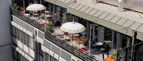 Une terrasse sur le toit avec des sièges extérieurs, un espace couvert et un bâtiment doté de grandes fenêtres.