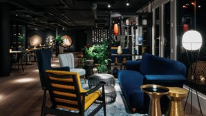 Un interior moderno con un sofá azul, una silla amarilla y una mesa redonda.