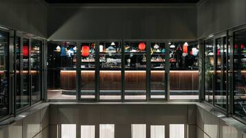 A modern bar area with glass partitions, a counter, and various lighting fixtures.