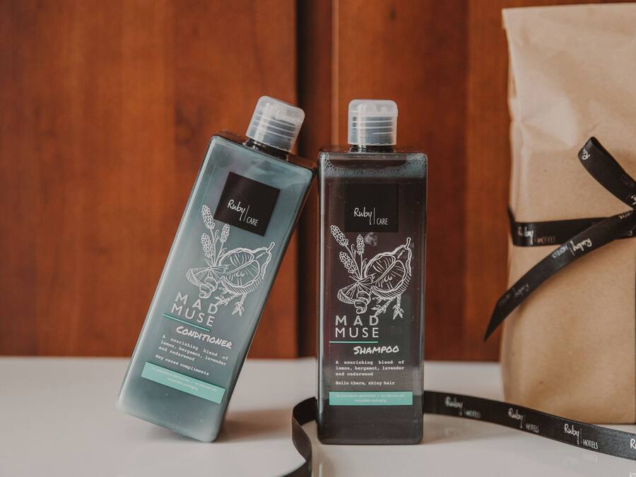 Dos botellas de productos Mad Muse Ruby Care, una bolsa de regalo y un lazo.