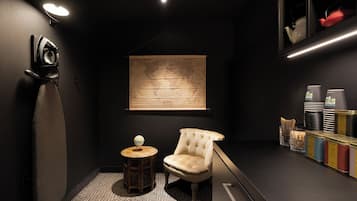 Een donkere kamer met een wereldbol op een tafeltje, een gestoffeerde fauteuil en een wereldkaart aan de muur.