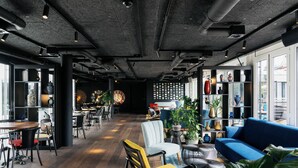 A modern interior with a wooden floor, seating areas, and a blue sofa. - Ruby Claire Hotel Geneva by IHG (Geneva)
