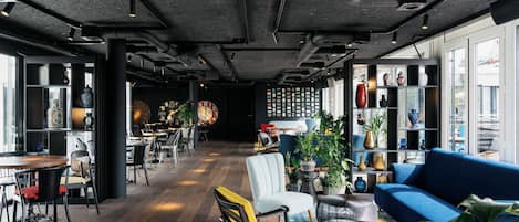 A modern interior with a wooden floor, seating areas, and a blue sofa.