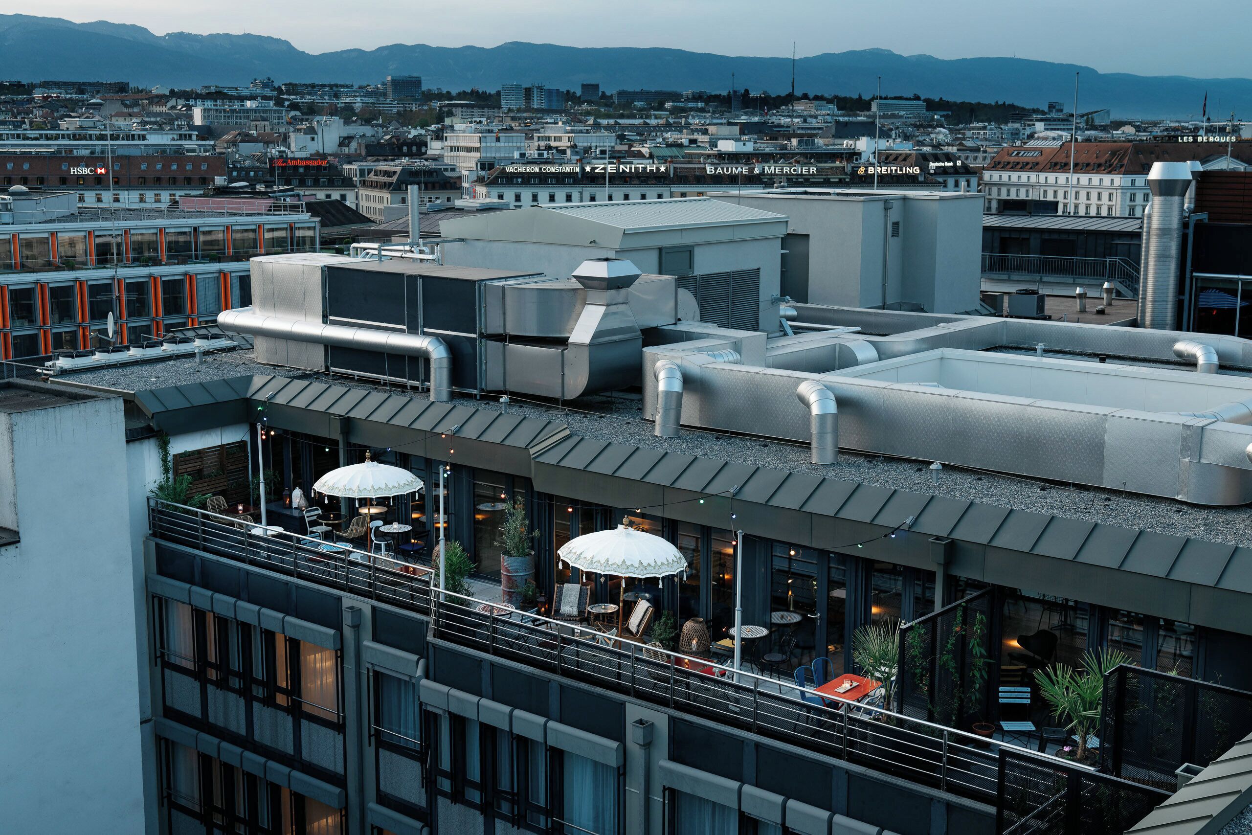 Una terraza en la azotea con mobiliario exterior, ventanas amplias y vistas a la ciudad.