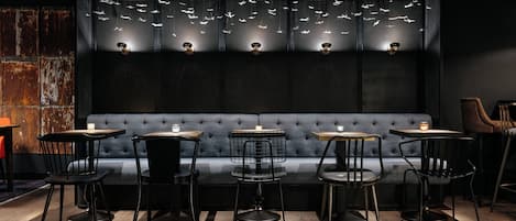 A restaurant with a dark interior, a blue cushioned bench, and multiple tables with chairs.