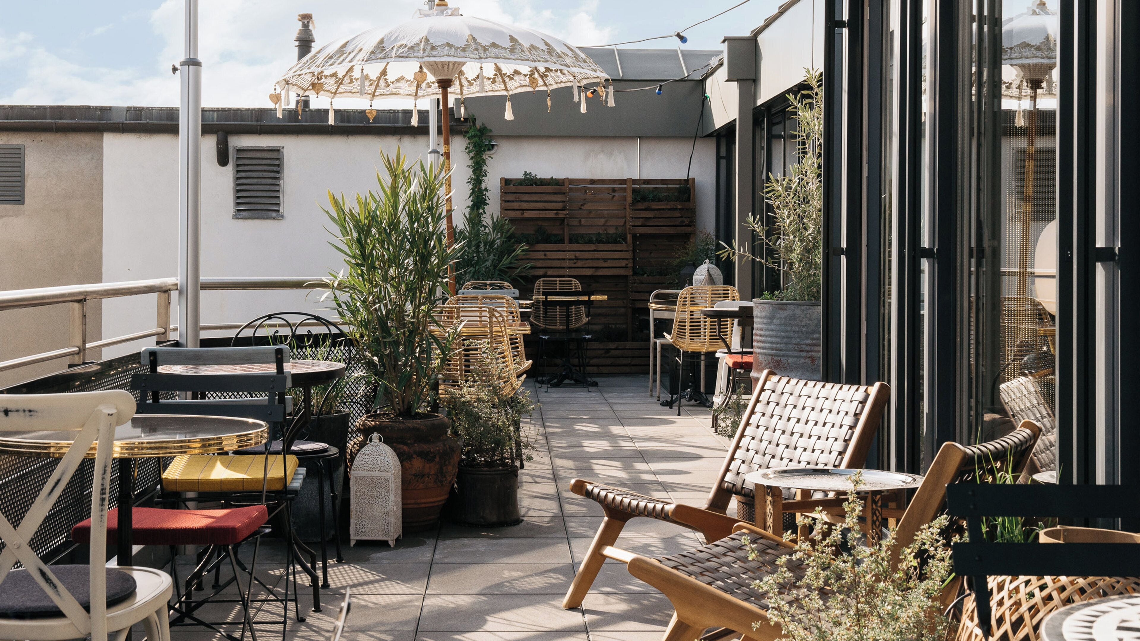 An outdoor patio with wicker furniture, potted plants, and a decorative umbrella.