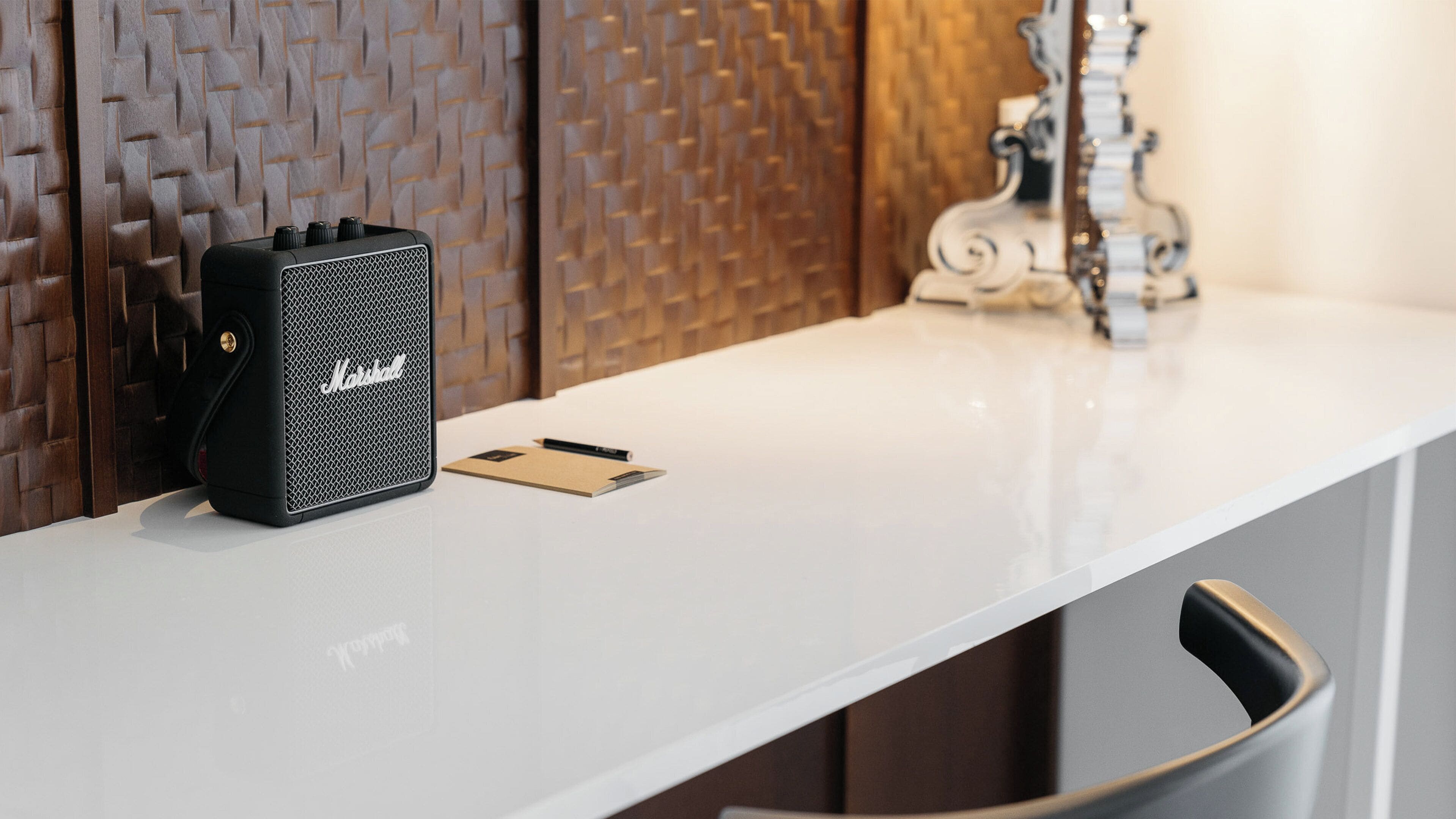 A white table with a black Marshall amplifier, a pencil, and a notebook.