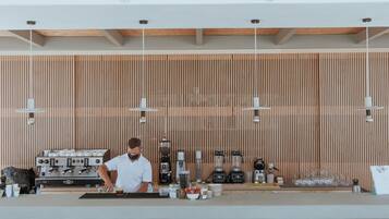 Un bar moderno con un barista che prepara bevande, una macchina da caffè e diversi strumenti da bar.