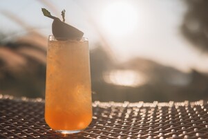 A tall glass with a beverage on a metal surface.