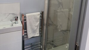 A bathroom with a glass shower, a white sink, and a towel rack. - City Centre, Detached 10 Person Accommodation (Liverpool)