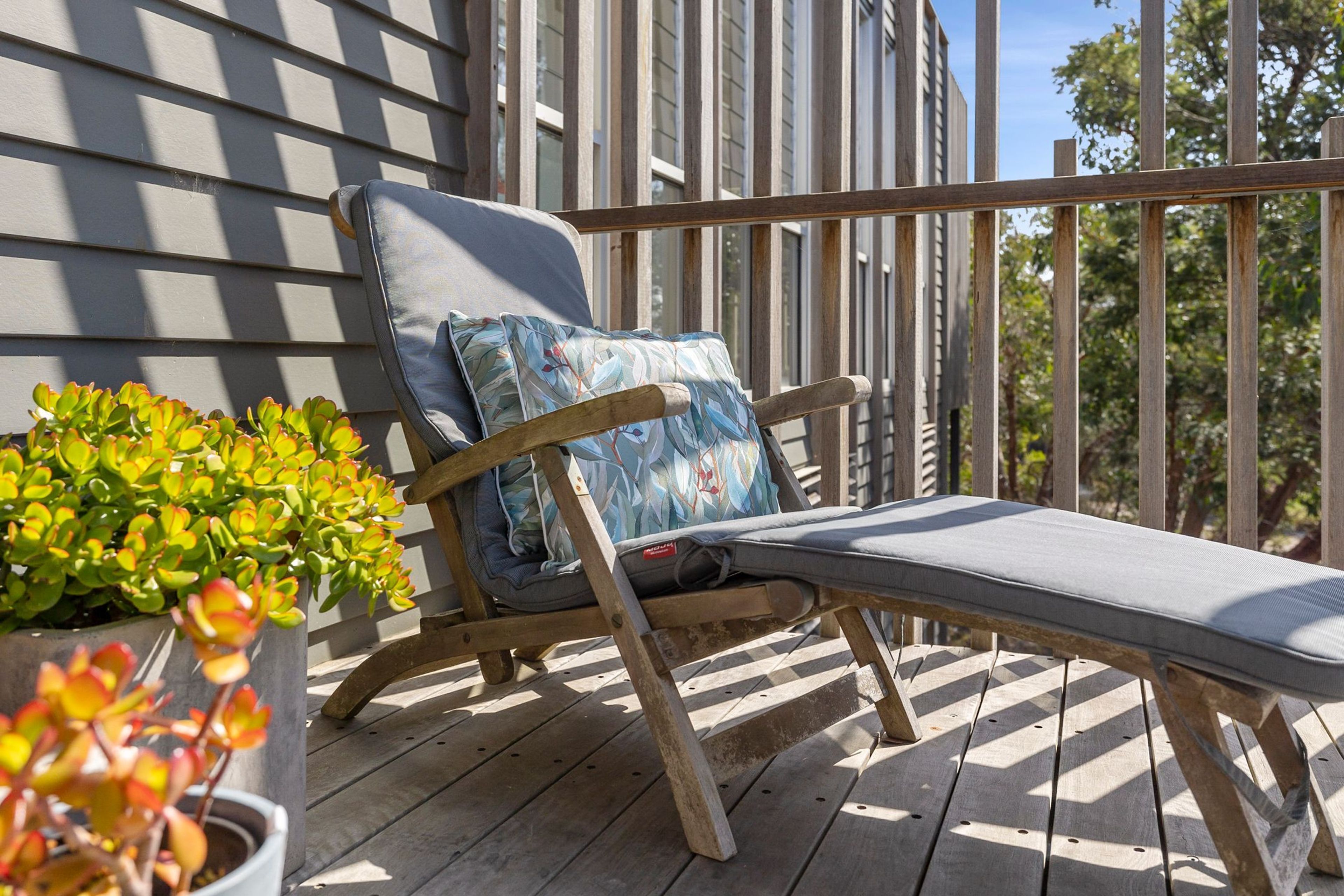 Eine Holzterrasse mit einem Liegestuhl, ausgestattet mit Kissen und Kopfstütze.
