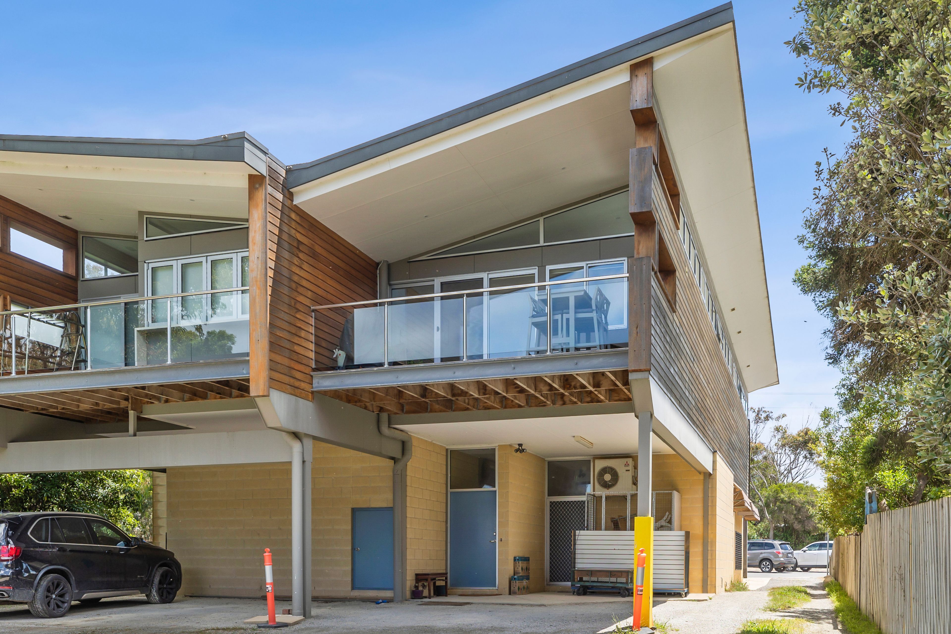 A modern two-story building with a flat roof, large windows, and a balcony.