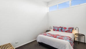Une chambre à coucher avec un lit, une table de chevet, une lampe et une fenêtre.