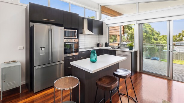 A modern kitchen with a large island, stainless steel appliances, and a view of the outdoors.