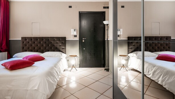 Habitación de hotel con dos camas, una puerta negra y un espejo.