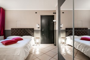 Une chambre d’hôtel avec deux lits, une porte noire et un miroir.