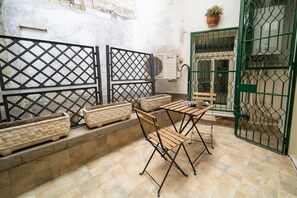 Un patio con una mesa, sillas, una planta en maceta y un portón verde.