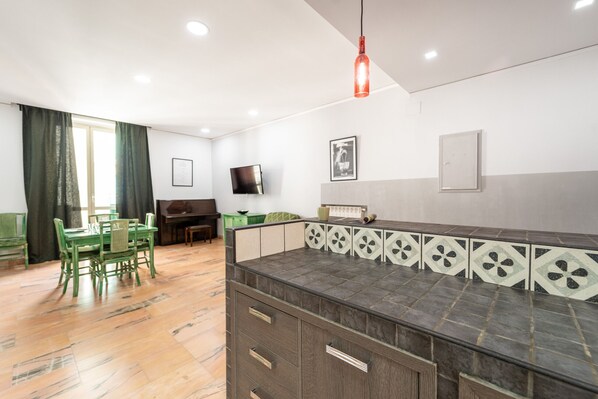 Una habitación moderna con una isla de cocina, mesa de comedor, sillas y un televisor.