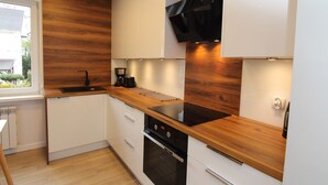Una cocina moderna con detalles de madera, electrodomésticos integrados y un ventanal que aporta luz natural.