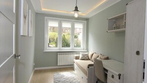 Una habitación pequeña y luminosa con cama, escritorio y radiador.