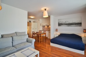 A compact living space with a sofa, a bed, a dining area, and a kitchen.