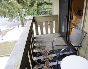 Enjoy a peaceful moment on this balcony with a chair and table, overlooking a serene tree.